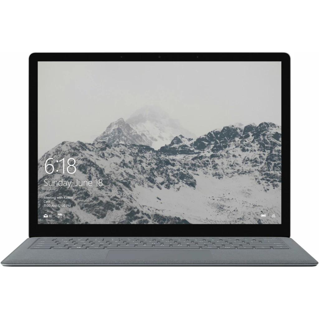 En Microsoft Surface Laptop 1Gen, der viser et sneklædt bjerglandskab på sin skærm, med et digitalt ur, der viser 6:18 og datoen søndag den 18. juni.