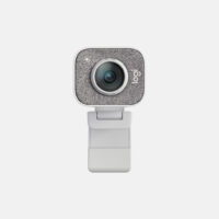 Forsiden af et Logitech-webkamera med en struktureret sølvfarvet frontplade, en linse i midten og en hvid, justerbar klips i bunden på en almindelig lys baggrund.